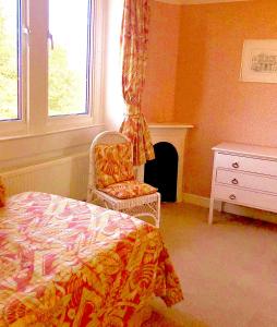 a bedroom with a bed and a chair and a window at Lauras Townhouse Apartments Dressmakers Salon in Bath
