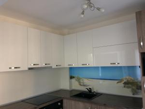 a kitchen with white cabinets and a fishtank at Апартамент Мони in Burgas City