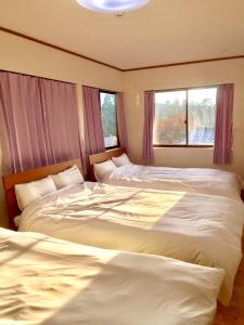 1 dormitorio con 2 camas y 2 ventanas en 天ゆふ(Ten Yufu) en Yufuin