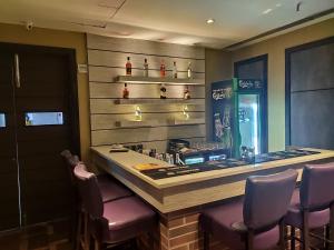 a bar with purple chairs and a soda machine at Pal Heights Mantra in Bhubaneshwar