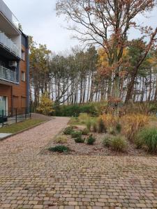 a brick walkway in front of a building with trees at DWIE SOSNY-Apartament na wydmie - 365PAM in Ustronie Morskie