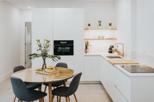 cocina blanca con mesa de madera y sillas en Céntrico estudio junto al Parque García Sanabria, en Santa Cruz de Tenerife