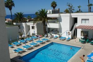 uma piscina com espreguiçadeiras e um hotel em Apartamentos El Sombrero em Acantilado de los Gigantes