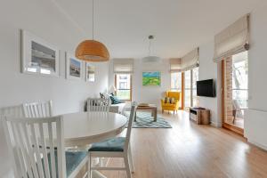 a kitchen and living room with a white table and chairs at Gdansk Comfort Apartments Bursztynowa in Gdańsk