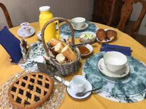 einen Tisch mit einem Korb Brot, Tassen und Essen in der Unterkunft Il Fiordaliso in Massa e Cozzile