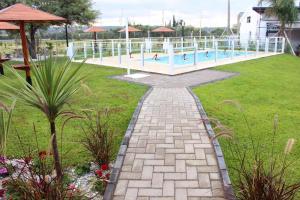 a swimming pool in a park with a brick pathway at Apart Del Cerro in Capilla del Monte