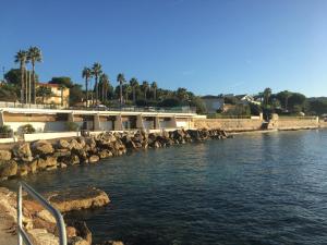 a body of water with rocks and a building at A l' orée de l'ô in La Ciotat