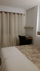 een slaapkamer met een bed, een bureau en gordijnen bij Habitacion con baño privado in Santa Cruz de Tenerife