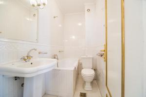 Baño blanco con lavabo y aseo en Hotel Carpati Imparatul Romanilor, en Bucarest