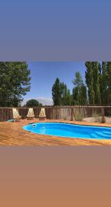 a swimming pool with chairs and a fence at Solanas de Uspallata in Uspallata