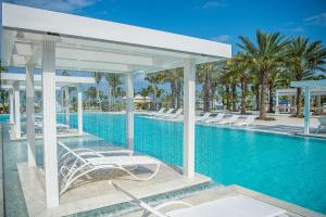 a pool at a resort with white chairs and trees at Grand Hyatt Baha Mar in Nassau