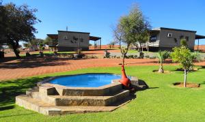 una estatua de pájaro sentada junto a una pequeña piscina en Eden Chalets en Windhoek