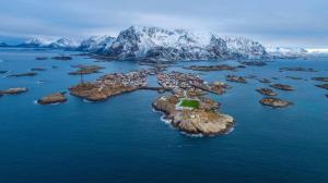 an island in the ocean with a snow covered mountain at Fast Hotel Henningsvær in Henningsvær