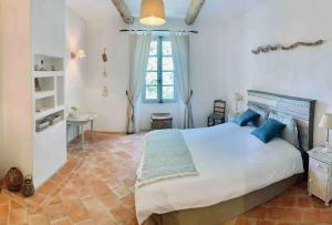 1 dormitorio con 1 cama blanca grande con almohadas azules en La Bastide en Saint-Julien