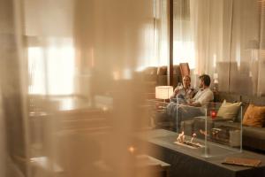 a man sitting on a couch in a living room at St. Martins Therme & Lodge in Frauenkirchen