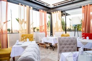 マラケシュにあるMedina Loft & Spaの白いテーブルと椅子、大きな窓のあるレストラン