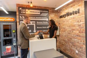 a man and a woman standing at a cash register at Easyhotel Reading in Reading