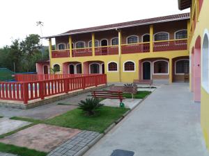 a yellow building with benches in front of it at Chalés Bandeiras in Ubatuba