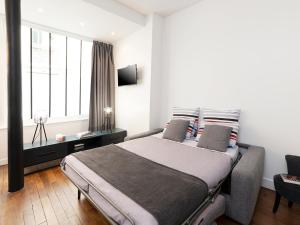 een slaapkamer met een bed en een groot raam bij Studios de Charme à Montmartre in Parijs