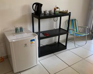 una pequeña estantería negra junto a una nevera pequeña en Quartos Anavilhanas, en Novo Airão