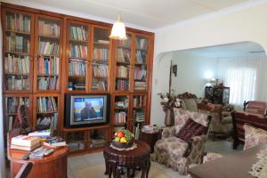 a living room with wooden book shelves filled with books at Dieu Donnee River Lodge in Port Shepstone