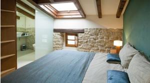 1 dormitorio con 1 cama grande y pared de piedra en Casa Rural Lakoak, en Garínoain