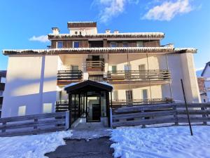 a building with snow in front of it at Hostdomus - Green Tech Apartment in Sestriere