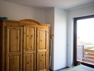 een slaapkamer met een houten kast en een raam bij Ferienwohnungen-Neue-Tiefe-Wohnung-Kleiderbuegel in Neue Tiefe Fehmarn