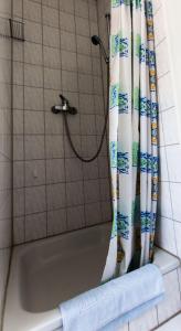 a bath tub with a shower curtain in a bathroom at Ferienwohnungen-Neue-Tiefe-Wohnung-Kleiderbuegel in Neue Tiefe Fehmarn
