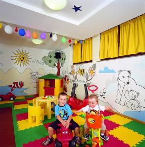 dos niños sentados en una habitación con coches de juguete en Hotel De la Ville, en Andalo