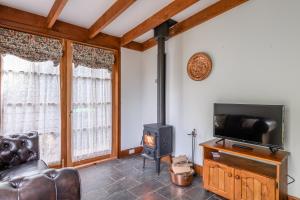 ein Wohnzimmer mit Kamin und Fernseher in der Unterkunft BRIDGE COTTAGES Sargeants & Armoury Cottages 1823 - HISTORY & CHARM in Richmond + 29 Fotos