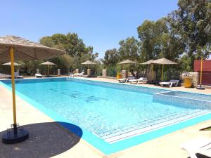 a large swimming pool with chairs and umbrellas at Camping & Hôtel Le Calme in Essaouira