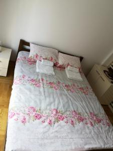 ein Bett mit rosa Blumen darauf in einem Schlafzimmer in der Unterkunft Apartman Downtown in Vrnjačka Banja + 11 Fotos