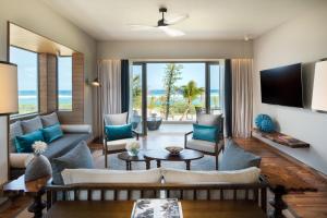 a living room with a couch and a tv at Anantara Iko Mauritius Resort & Villas in Blue Bay