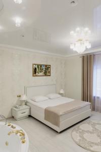 um quarto branco com uma cama grande e uma banheira em Отель "Даймонд Луговая" em Kursk