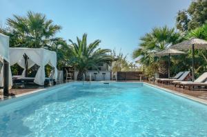 a swimming pool with chairs and palm trees at Valena Mare Suites & Apartments in Plaka