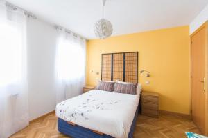 ein Schlafzimmer mit einem Bett und einer gelben Wand in der Unterkunft Homelike Plaza Mayor in Madrid