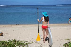 a girl in a hat holding two paddles on the beach at La Villa de la Plage in La Saline les Bains