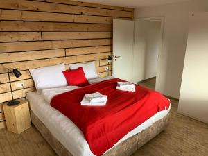 ein Schlafzimmer mit einem großen Bett mit einer roten Decke in der Unterkunft Kuckucksnester Rötenbach in Friedenweiler