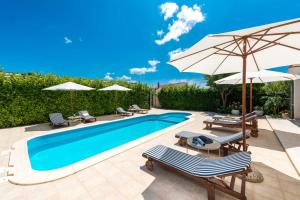 a swimming pool with umbrellas and chairs and a pool at Holiday Home Floreat in Orebić