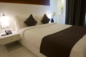 a bedroom with a large bed and a phone on a table at Boon Inn in Malappuram