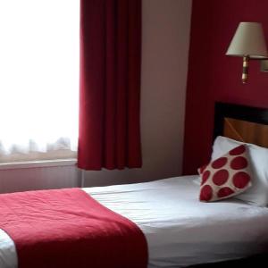 a bedroom with a bed with red walls and a window at Britannia Hotel Newcastle Airport in Newcastle upon Tyne