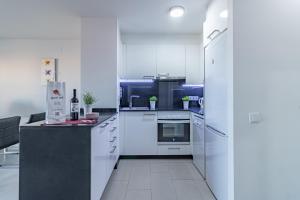 una cocina blanca con armarios y electrodomésticos blancos en Apart-rent Apartamento Port Grec 0175, en Empuriabrava