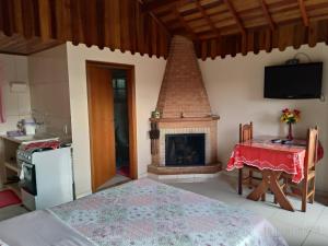 a living room with a fireplace and a table and a bed at Monte Verde MG - Ana Júlia Chalés in Monte Verde