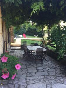 un patio con mesa, sillas y flores rosas en Maison en Périgord à 5 mn à pieds du centre Sarlat, en Sarlat-la-Canéda