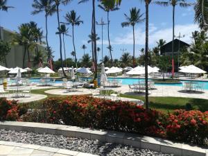 uma piscina de resort com mesas, cadeiras e palmeiras em Marulhos Resort Porto De Galinhas em Porto de Galinhas