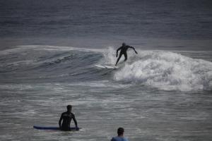 un hombre montando una ola en una tabla de surf en el océano en Tayought Surf House, en Taghazout