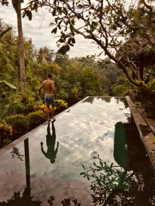 un uomo che cammina sulla cima di una piscina di Alami Villa ad Ubud