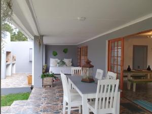 een patio met een tafel en stoelen en een bed bij GUINEA FOWL in Plettenbergbaai