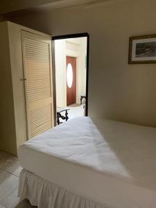a large white bed in a room with a doorway at Beach Vue Barbados in Bridgetown